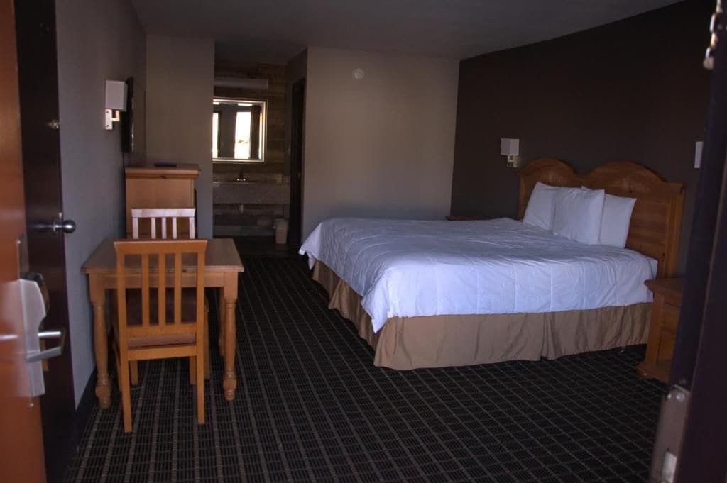 Una habitación de hotel con una cama, un escritorio y una silla.