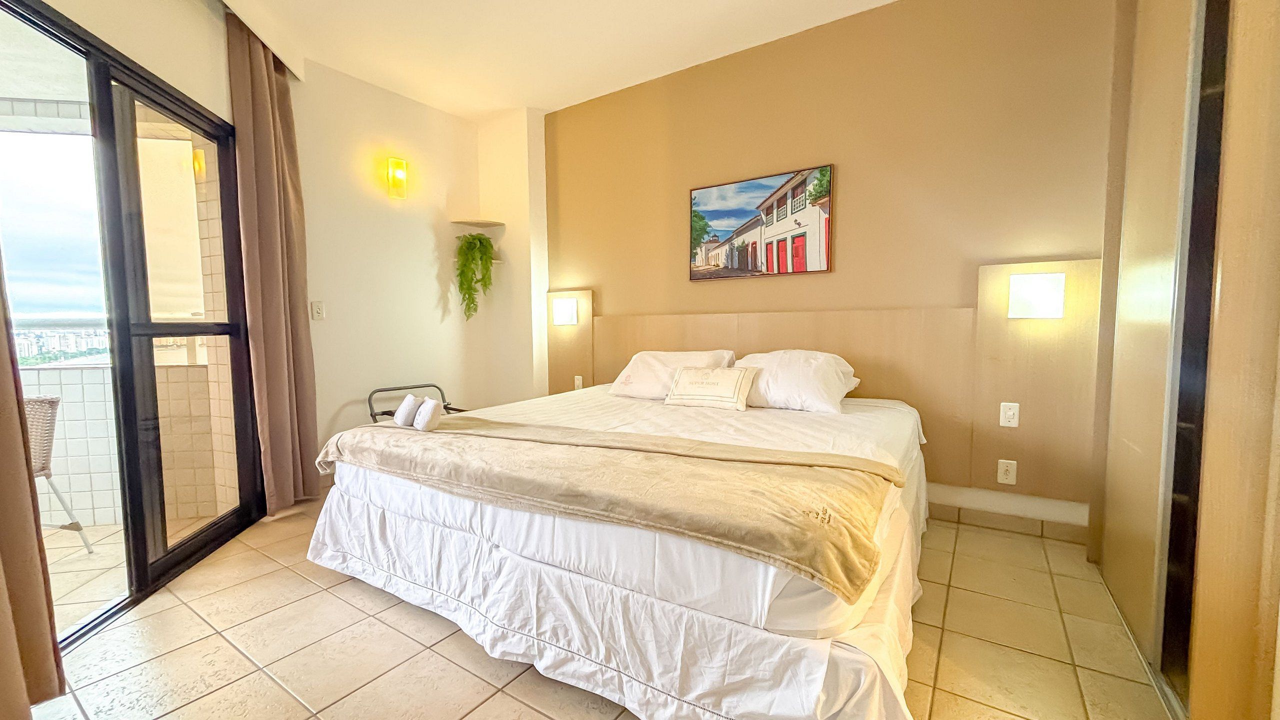 Une chambre d’hôtel avec un lit, un tableau au mur et une vue à travers la porte vitrée.