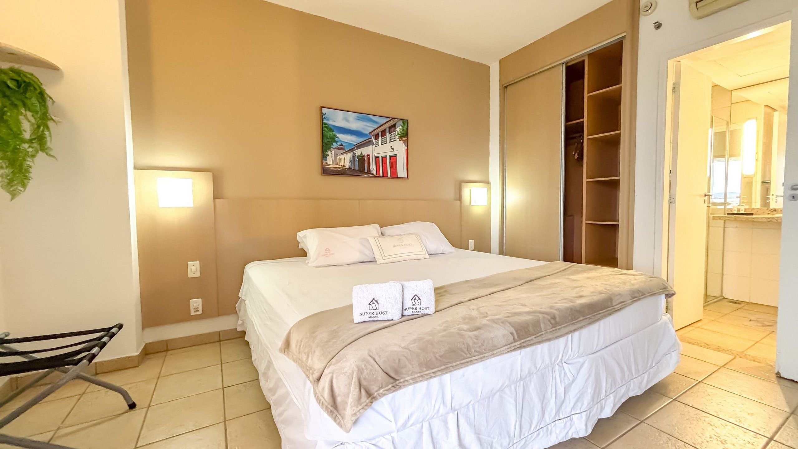 Una habitación de hotel con una cama, una silla, un cuadro y un armario.