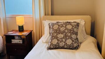 A neatly made bed with a floral pillow, a bedside lamp, and a framed picture on the wall.
