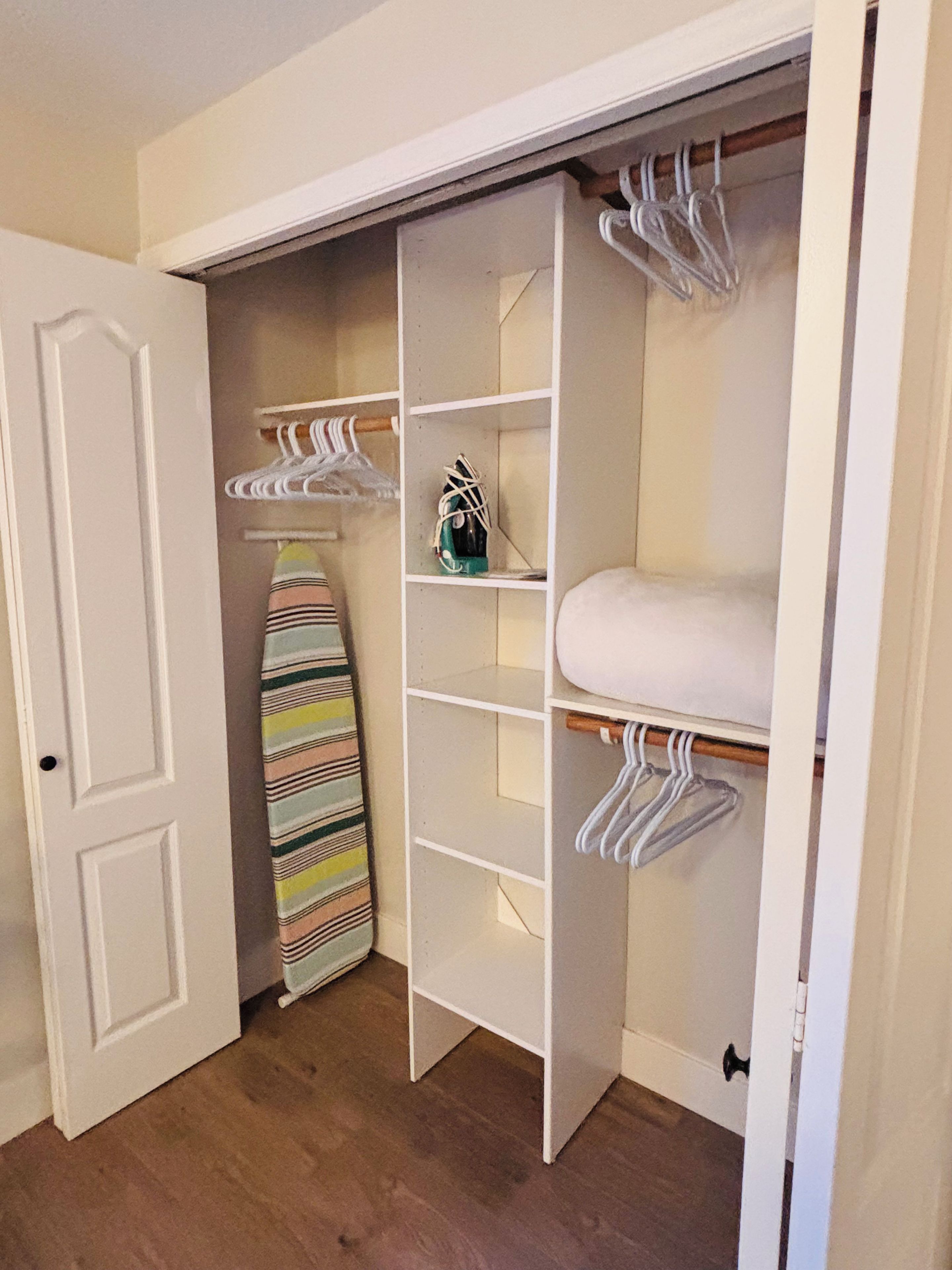 Ein begehbarer Kleiderschrank mit offenen Türen, Regalen und Kleiderstangen.