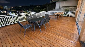 Eine Holzterrasse mit Tisch und Stühlen, umgeben von einem weißen Geländer.