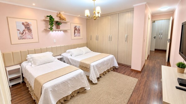 Un dormitorio con dos camas, un armario, un escritorio y un televisor.