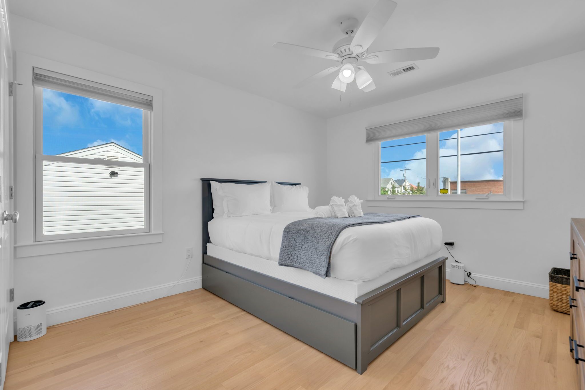Una camera da letto con un letto, una ventola a soffitto e due finestre.