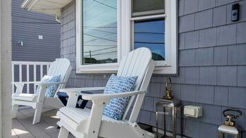 Twee witte Adirondack-stoelen met blauwe kussens op een houten terras.