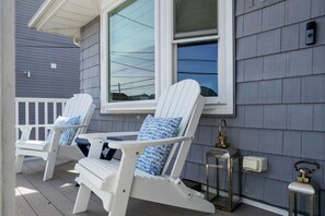 Deux chaises Adirondack blanches, dotées de coussins bleus, sur une terrasse en bois.