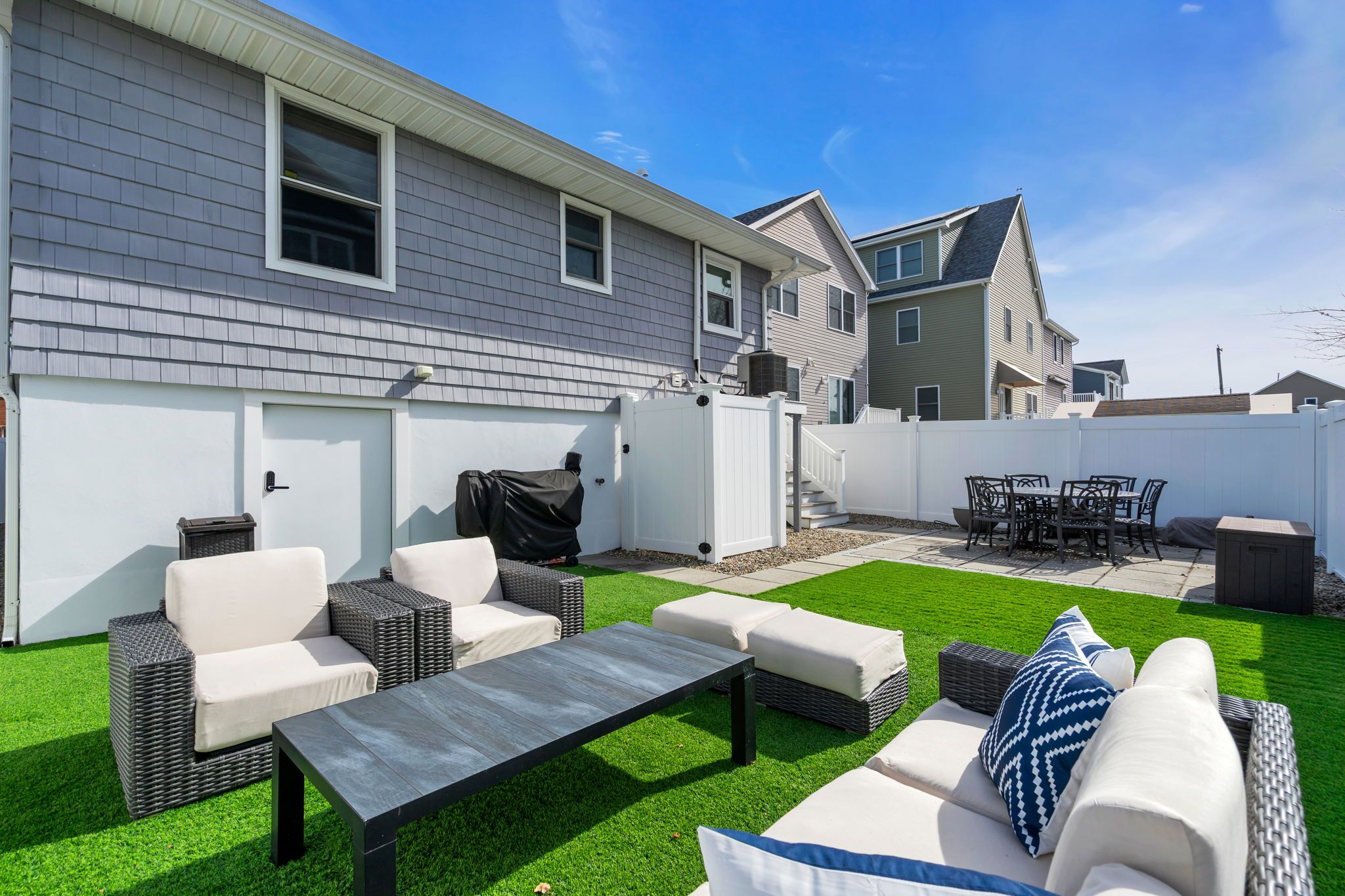 Un jardin avec un espace patio, du mobilier d’extérieur et une pelouse bien entretenue.