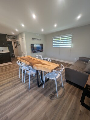 Eine moderne Küche mit dunklen Schränken, einem Holztisch und weißen Stühlen.