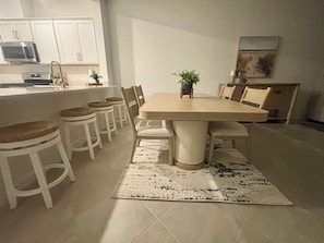 A dining area with a large table, six chairs, a small potted plant, and a kitchen in the background. -     Beautiful 3-Bedroom Villa with Lake & Golf Course Views (Punta Gorda)
