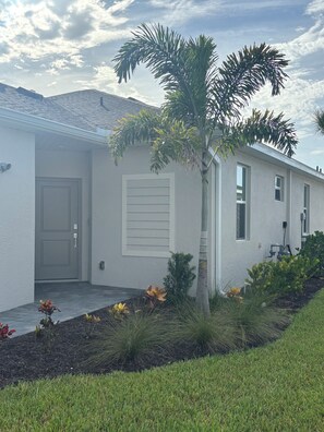 A single-story house with a front door, a window, and a small tree. -     Beautiful 3-Bedroom Villa with Lake & Golf Course Views (Punta Gorda)