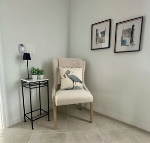 A corner room with a chair featuring a bird design pillow, a small table with a lamp and a plant, and two framed artworks on the wall. -     Beautiful 3-Bedroom Villa with Lake & Golf Course Views (Punta Gorda)