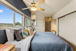 A bedroom with a large bed, a ceiling fan, and a view of the outdoors through the window. - Skyline Views, 2 Story Condo, Walk to Zilker & Barton Springs (Austin)