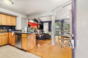 A modern kitchen with wooden cabinets, a dishwasher, and a dining area with a sofa and a coffee table. - Skyline Views, 2 Story Condo, Walk to Zilker & Barton Springs (Austin)