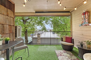 A balcony with artificial grass, a wicker chair, a table, and a decorative wall piece. - Skyline Views, 2 Story Condo, Walk to Zilker & Barton Springs (Austin)