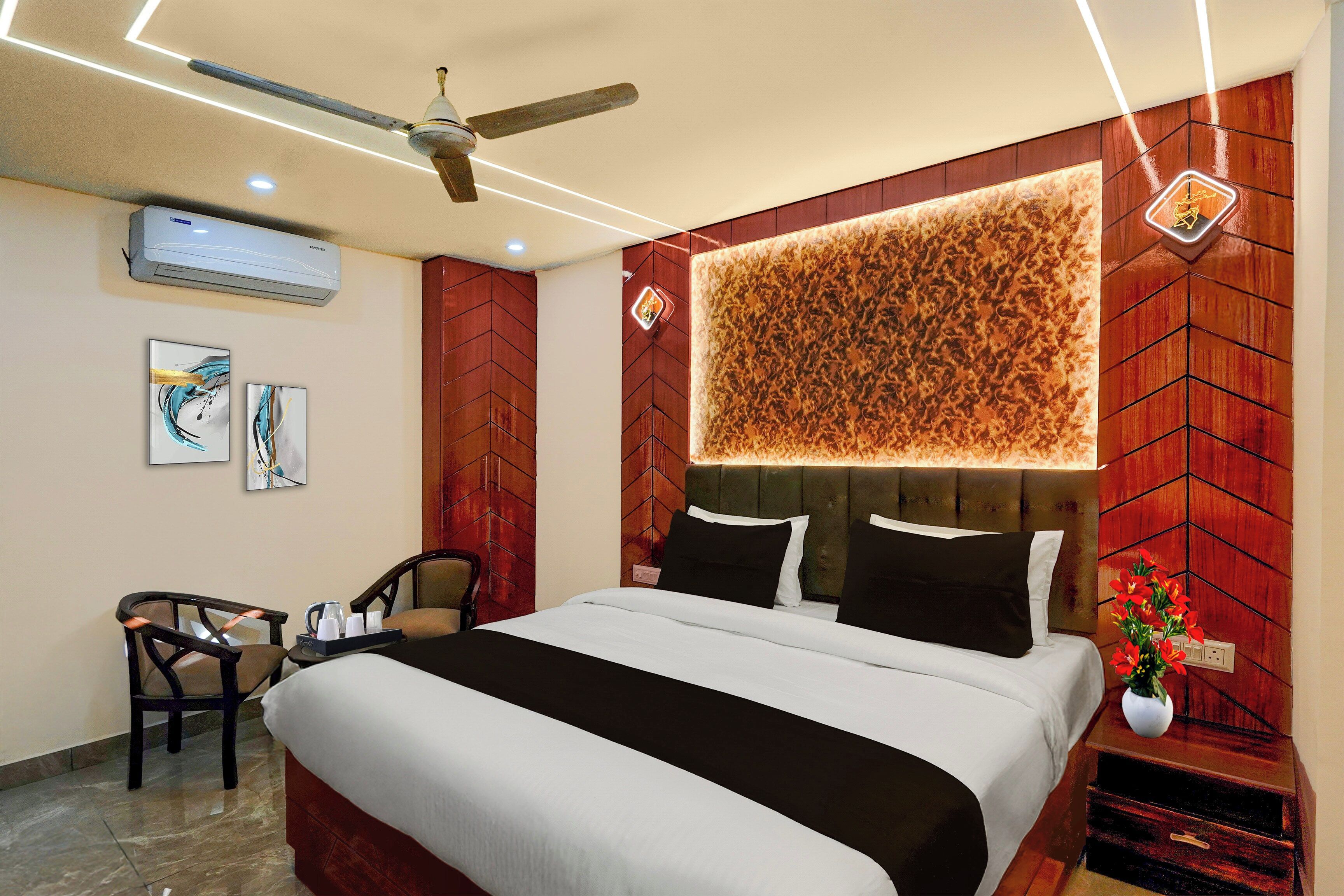 Habitación de hotel con cama, escritorio, silla, ventilador de techo y aire acondicionado instalado en la pared.