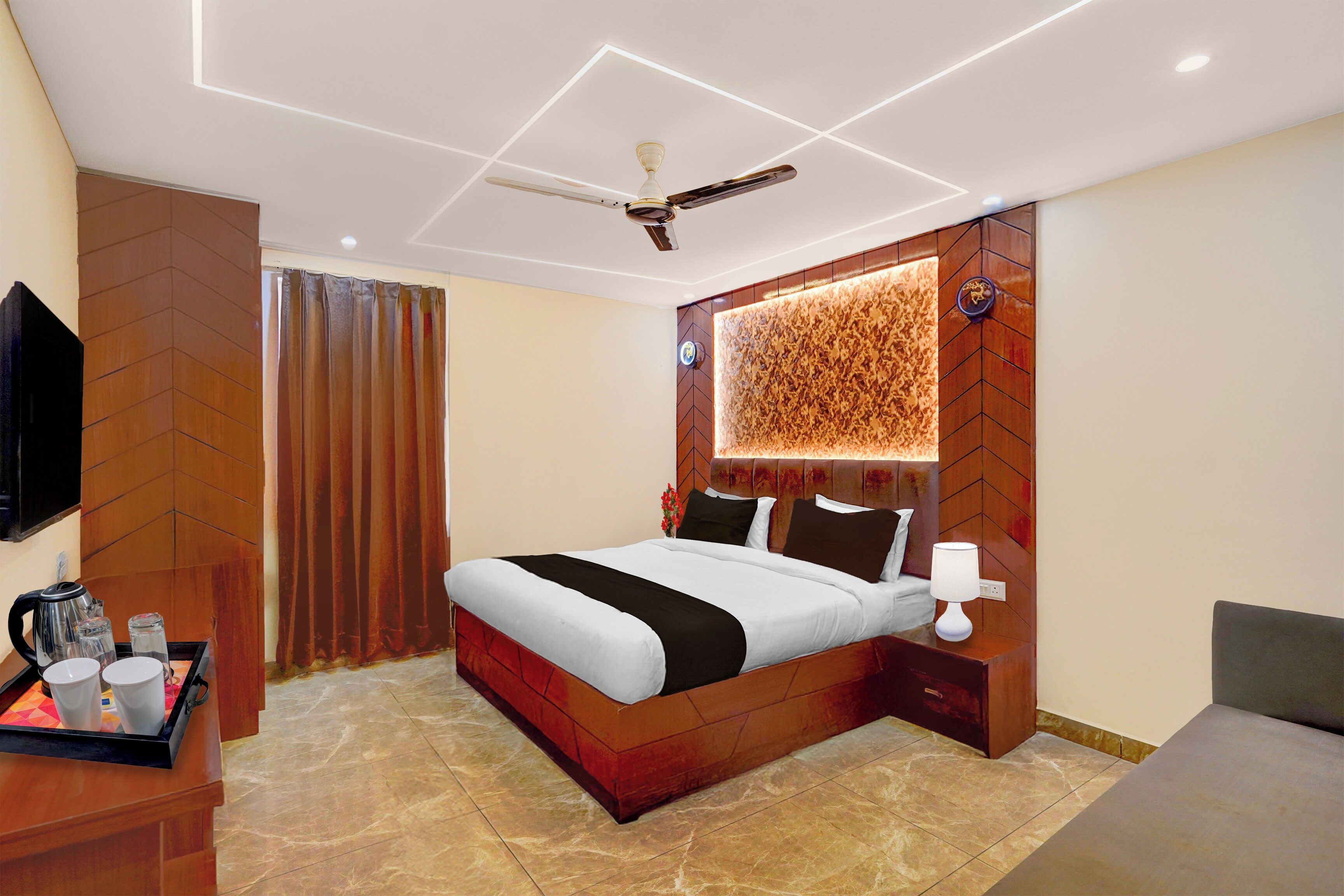 A modern hotel room with a bed, bedside table, lamp, and a ceiling fan.