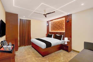 Una habitación de hotel moderna con una cama, mesita de noche, lámpara y ventilador de techo.