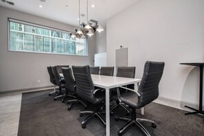 A conference room with a white table, black chairs, a modern chandelier, and a large window. - Affordable Suite | Steps to Subway & Parks (Toronto)