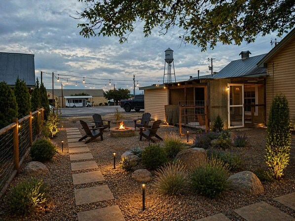 Un patio con mobiliario exterior, una chimenea y un edificio rústico con techo de metal.