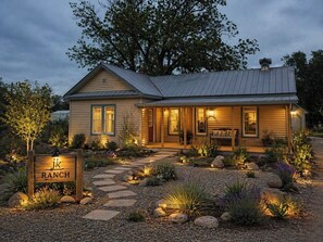 Una casa de estilo rancho con un porche, un sendero de piedra y un letrero que dice 'JK Ranch'.