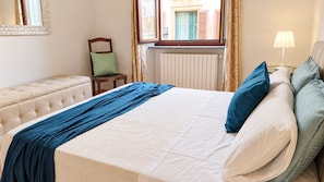 Una habitación de hotel con una cama, una silla, una lámpara y una ventana.
