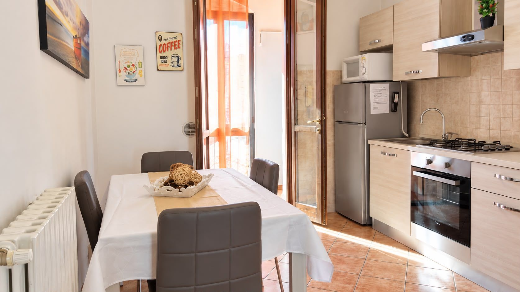 Een functionele keuken met een eettafel, stoelen, een koelkast, een magnetron en een oven.