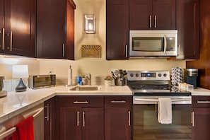 A modern kitchen with dark wood cabinets, stainless steel appliances, and a marble countertop. - Updated North Tahoe Studio | Pool, Spa & Pines (Tahoe Vista)