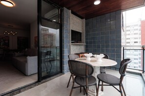 A modern living space with a glass door leading to an outdoor area, a round table with chairs, and a view of a cityscape. - New Listing (Rio de Janeiro)