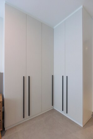 A room with a large white wardrobe, two black handles, and a wooden cabinet. - New Listing (Rio de Janeiro)