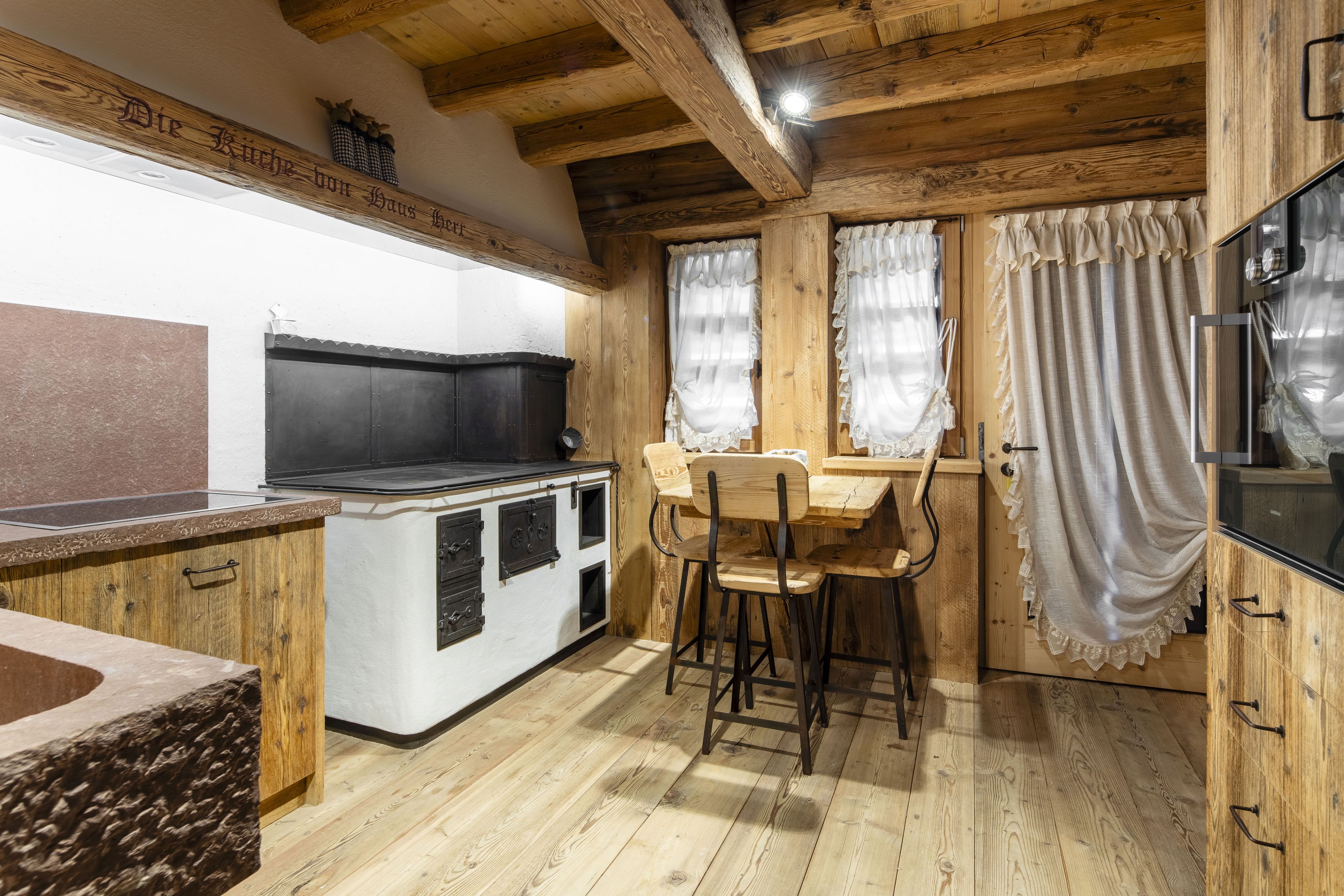 Una cocina rústica con vigas de madera, estufa y mesa de comedor con sillas.