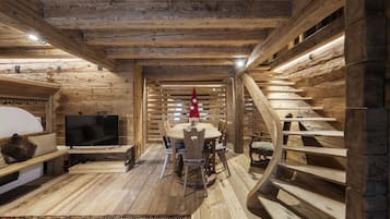 Un interno in legno con TV, tavolo da pranzo, sedie e una scala.