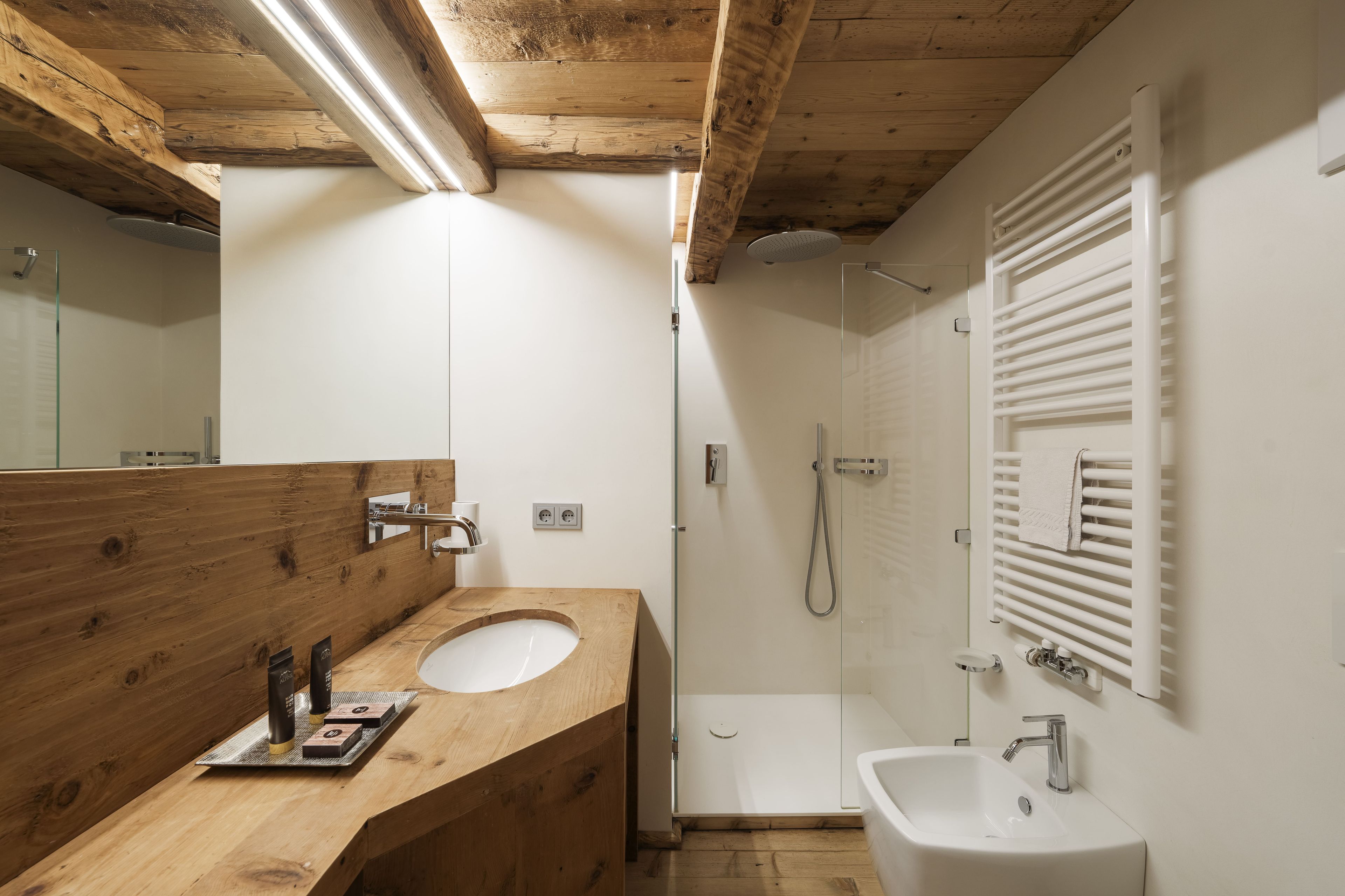 Un bagno con un mobile bagno in legno, un lavabo, una doccia e un bidet.