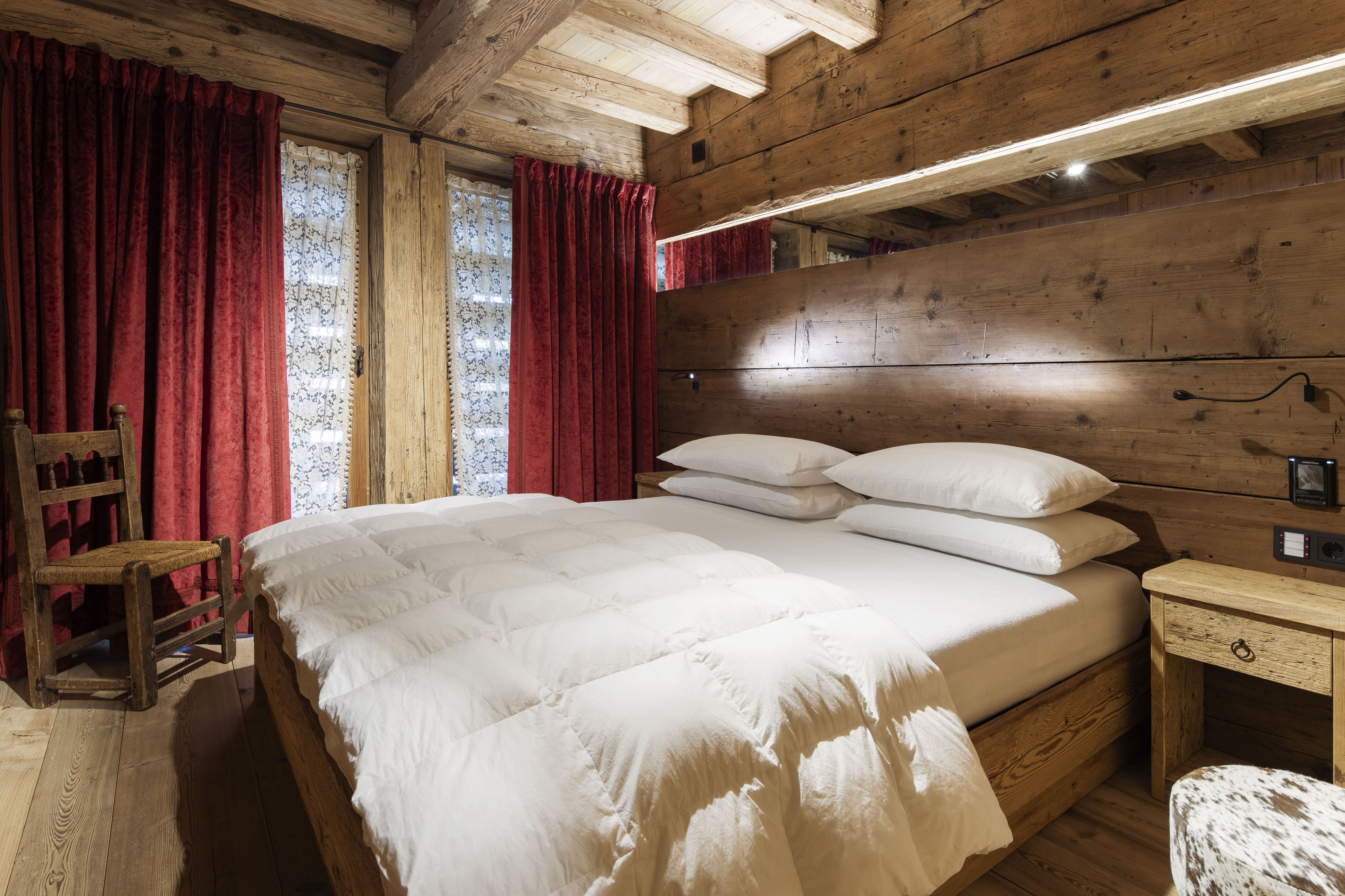 Una habitación de madera con una cama, una mesita de noche y una silla.