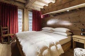 Quarto de madeira com uma cama, uma mesa de cabeceira e uma cadeira.