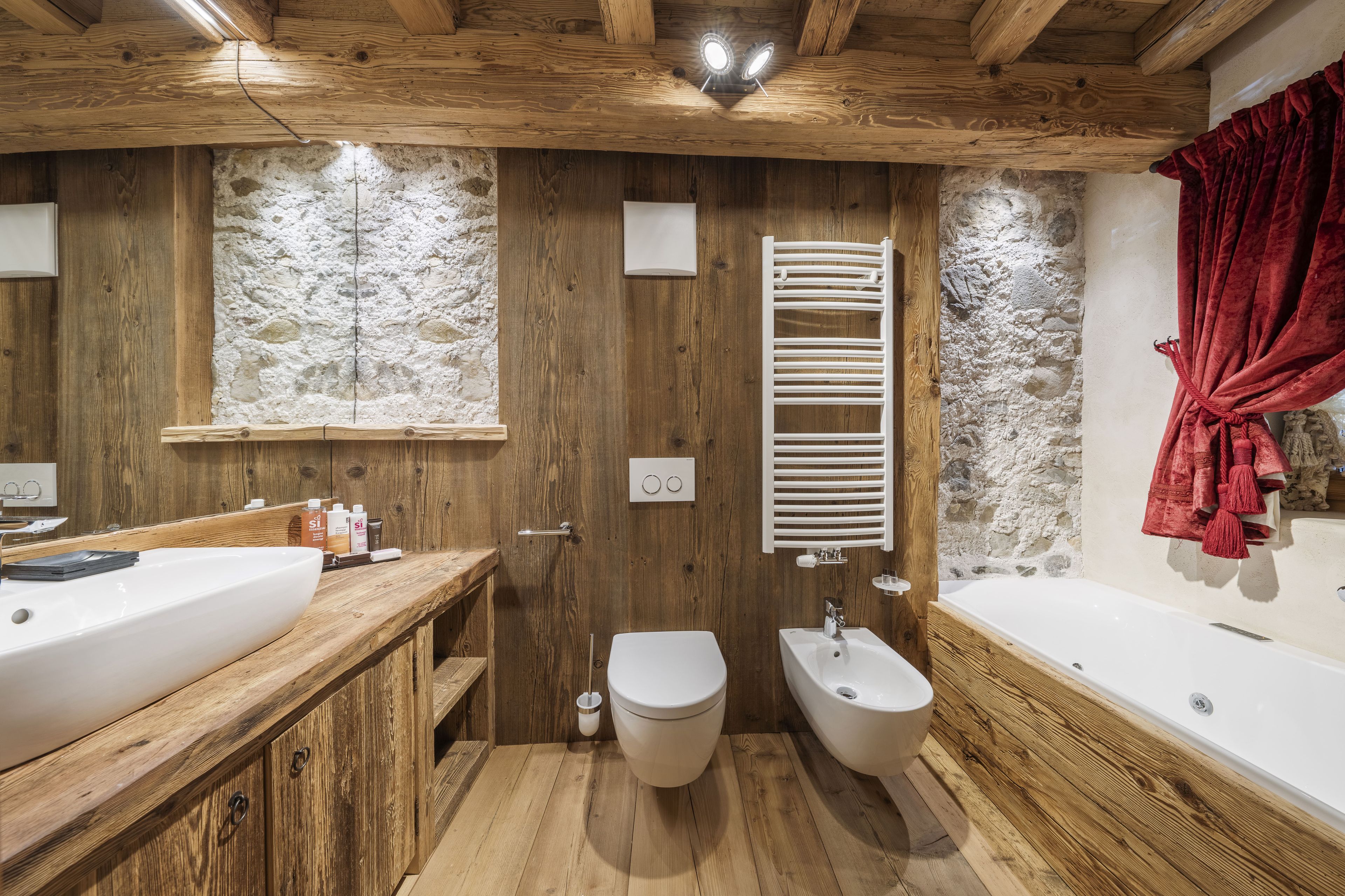 Un bagno in legno con una grande vasca, un bidet e un water.