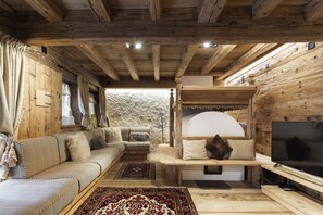 Un'accogliente stanza in legno con un divano, una televisione e un camino.