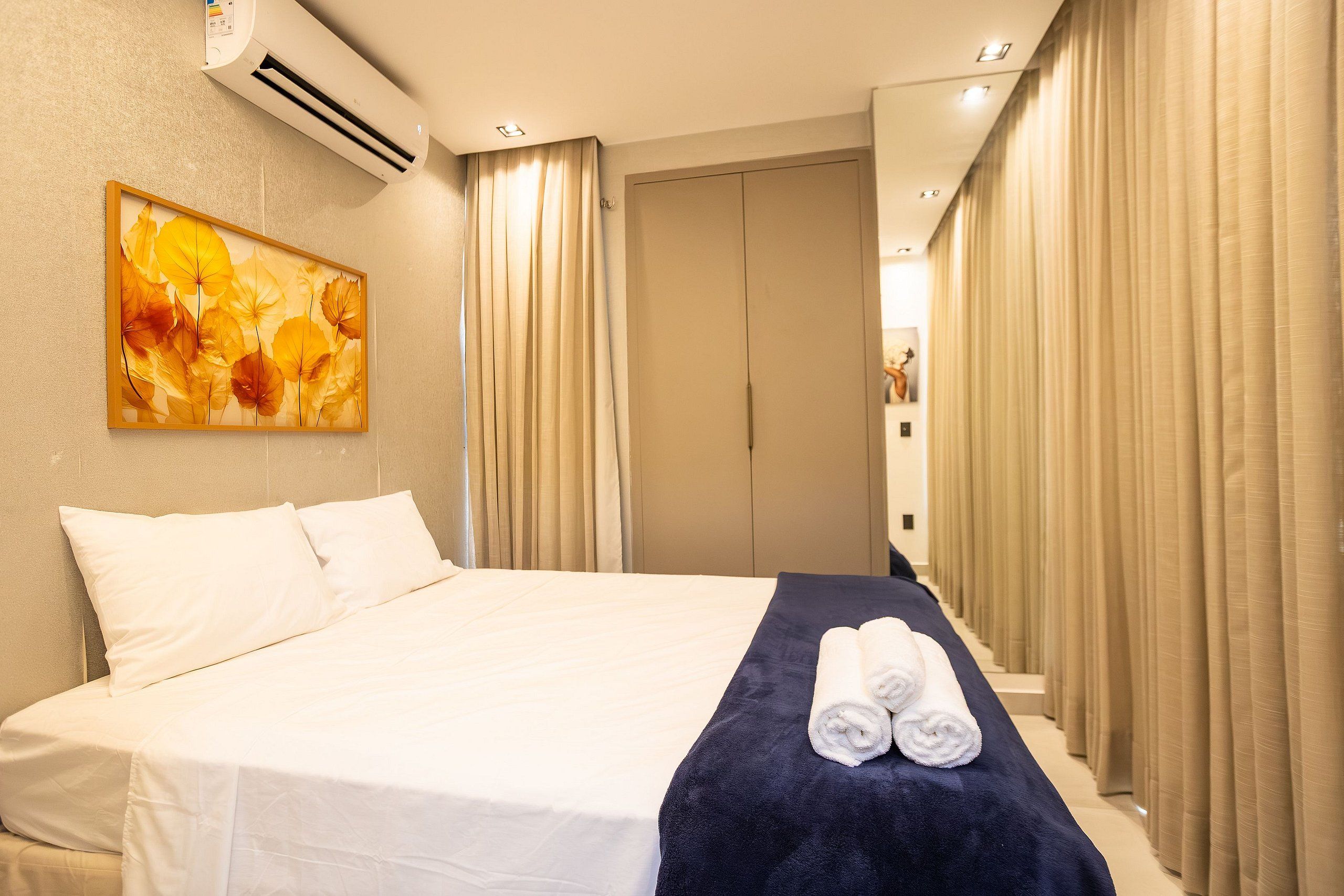 Una habitación de hotel con una cama, un cuadro y un juego de cortinas.