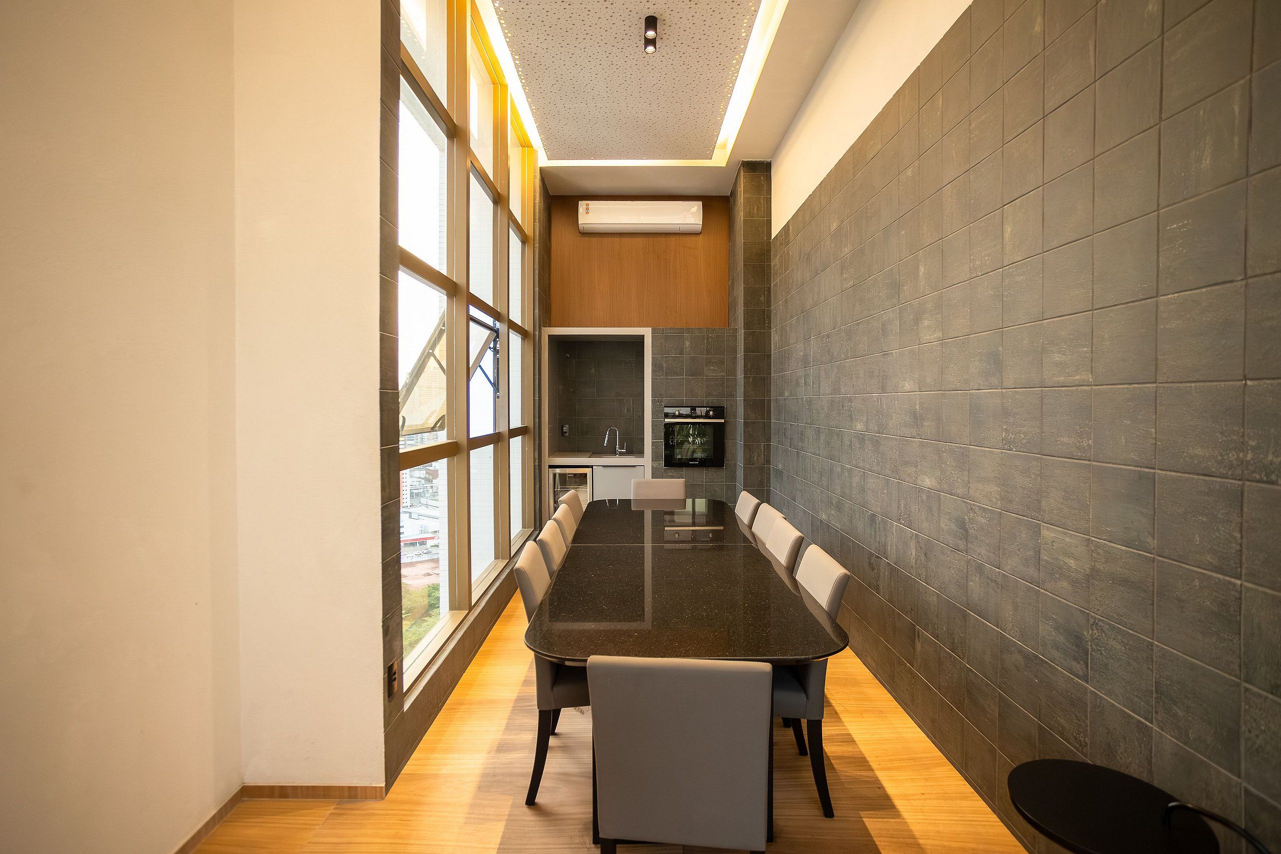 Una sala de reuniones moderna con una mesa larga, sillas y una zona de cocina al fondo.