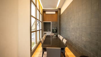 Una sala de reuniones moderna con una mesa larga, sillas y una zona de cocina al fondo.