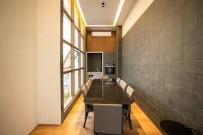 Una sala de reuniones moderna con una mesa larga, sillas y una zona de cocina al fondo.