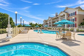A pool area with multiple swimming pools, lounge chairs, and umbrellas. - Pigeon Forge Condo with Balcony | Newly Renovated! (Pigeon Forge)
