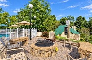 An outdoor patio area with stone seating, a fire pit, and umbrellas. - Pigeon Forge Condo with Balcony | Newly Renovated! (Pigeon Forge)