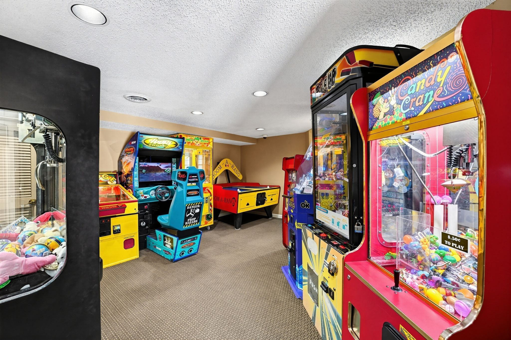 Una habitación con juegos de arcade, incluyendo una máquina de garra y juegos de carreras.