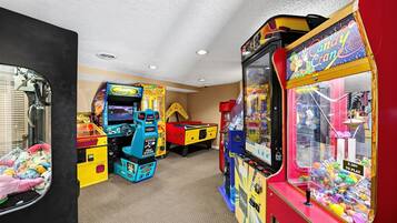 Una habitación con juegos de arcade, incluyendo una máquina de garra y juegos de carreras.