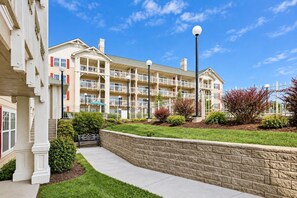 A multi-story residential building with balconies, a landscaped garden, and a paved walkway. - Mountain Cottage with Loft & Private Balcony (Pigeon Forge)