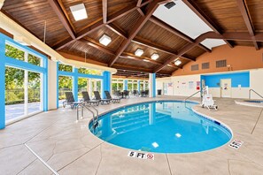 An indoor swimming pool with a 5 ft depth marker, lounge chairs, and a ceiling with wooden beams and skylights. - Mountain Cottage with Loft & Private Balcony (Pigeon Forge)