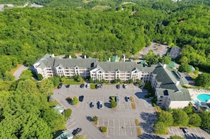 Ein mehrstöckiges Hotel mit Innenhof, Parkplatz und Schwimmbad.