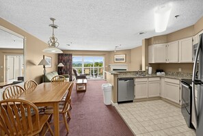 A spacious kitchen with a dining area, a view through the glass door, and a clean, modern design. - Spacious Condo with Fireplace & Full Kitchen (Pigeon Forge)