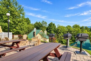 An outdoor patio area with picnic tables, chairs, and barbecue grills. - Cozy Pigeon Forge Condo w/ Kitchen & Balcony (Pigeon Forge)
