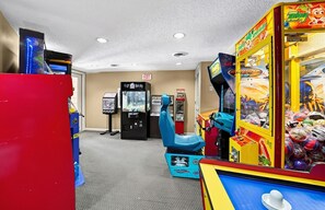 A room with arcade games, a vending machine, and a blue chair. - Pigeon Forge Renovated Condo w/ Private Balcony (Pigeon Forge)